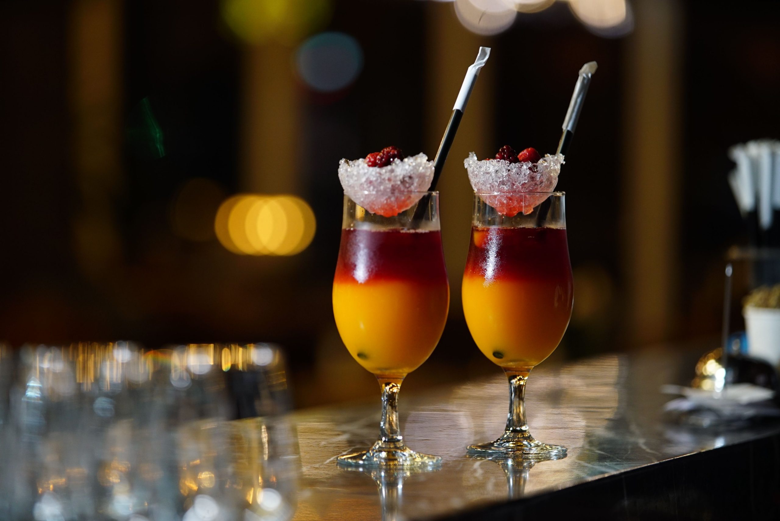 Two vibrant cocktails with berries and ice, set in a stylish bar setting.